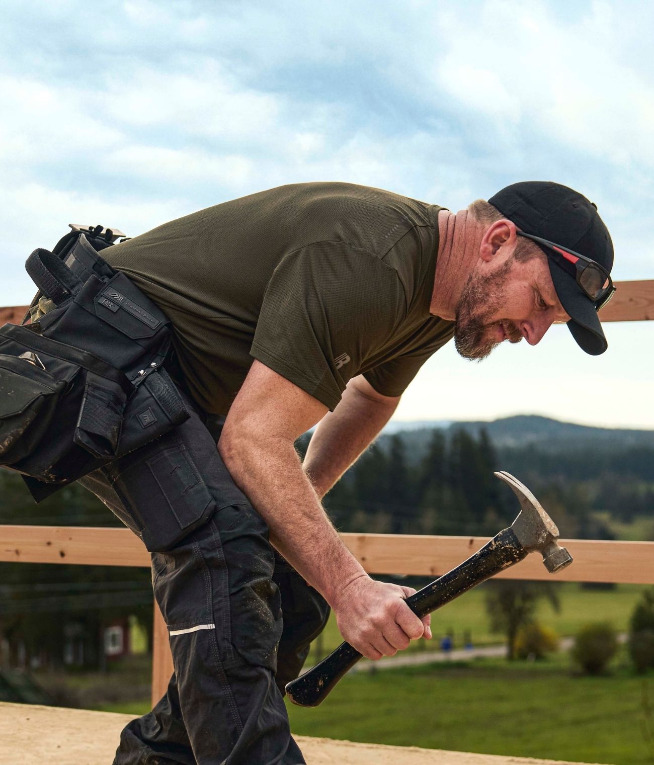 Blaklader Performance Sun T-Shirt in Forest Night and Ripstop Pants in Black worn by carpenter hammering nails on roof frame