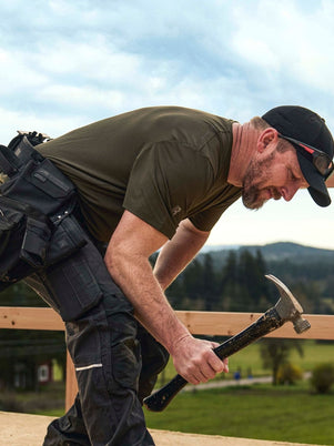 Blaklader Performance Sun T-Shirt in Forest Night and Ripstop Pants in Black worn by carpenter hammering nails on roof frame