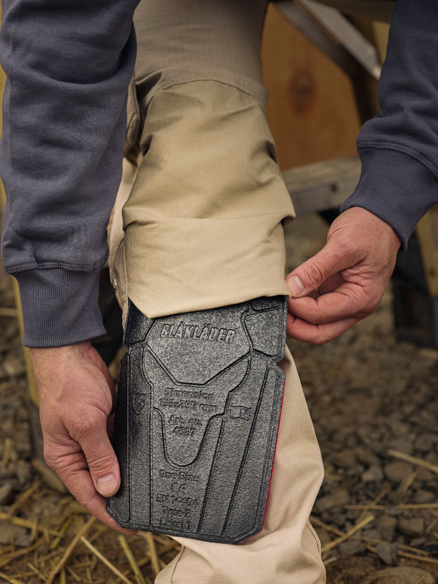 Tradesman inserting Blaklader kneepads in to workpants