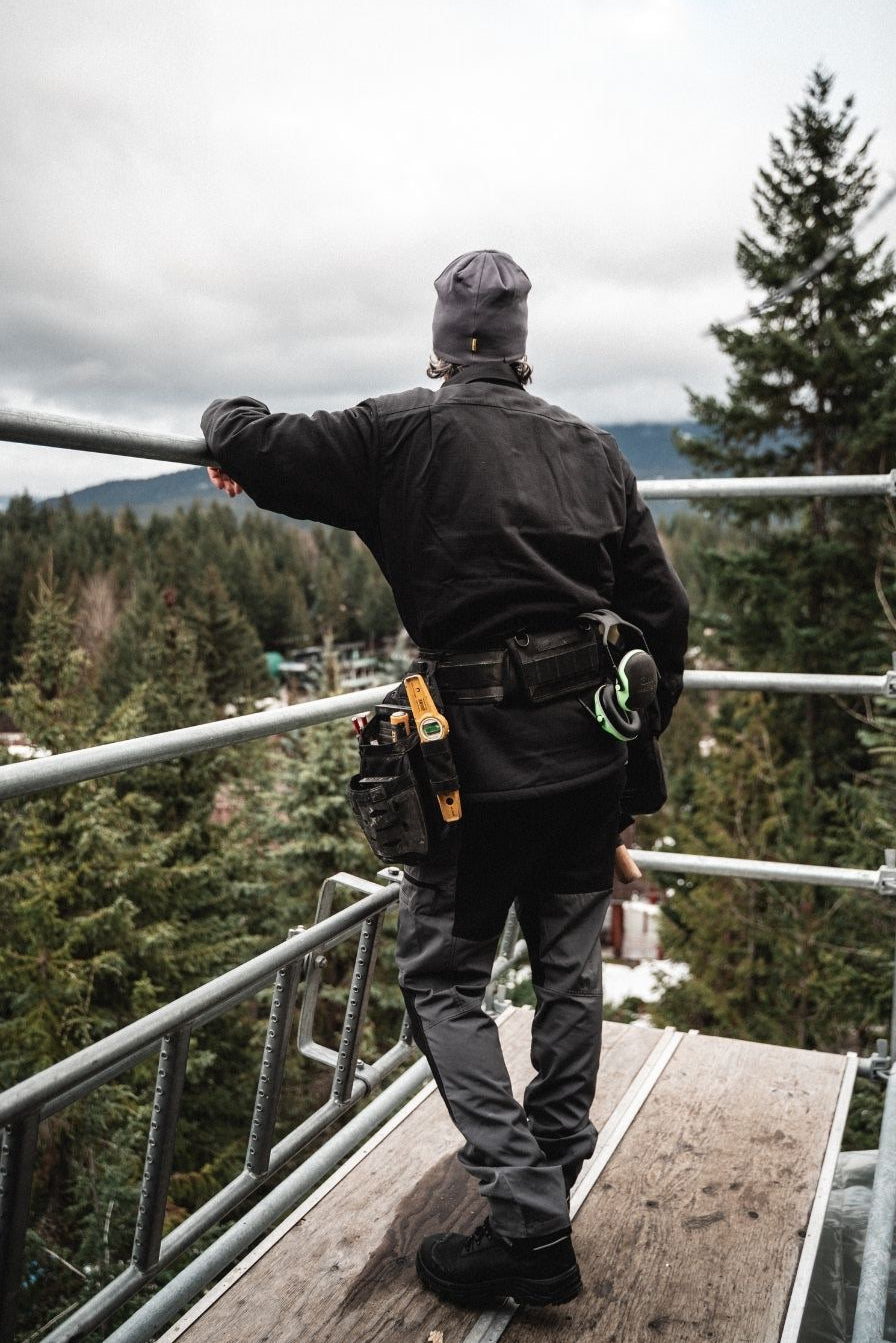 Tradesman wearing Blaklader Workwear and a toolbelt on construction site scaffolding
