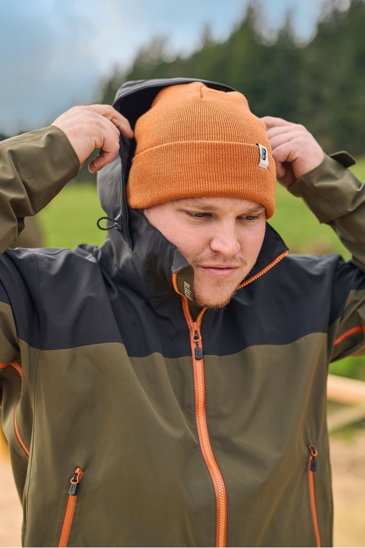 Blaklader Cascade Jacket in Forest Green Rust with adjustable hood worn by tradesperson on outdoor job site
