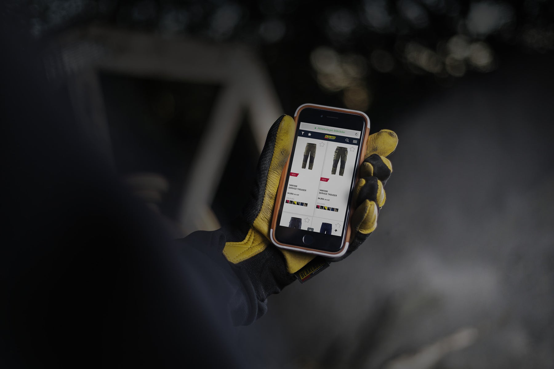 Hand wearing a yellow glove holding a smartphone with an app on a dark background