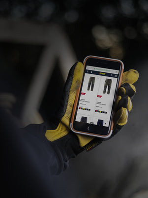 Hand wearing a yellow glove holding a smartphone with an app on a dark background