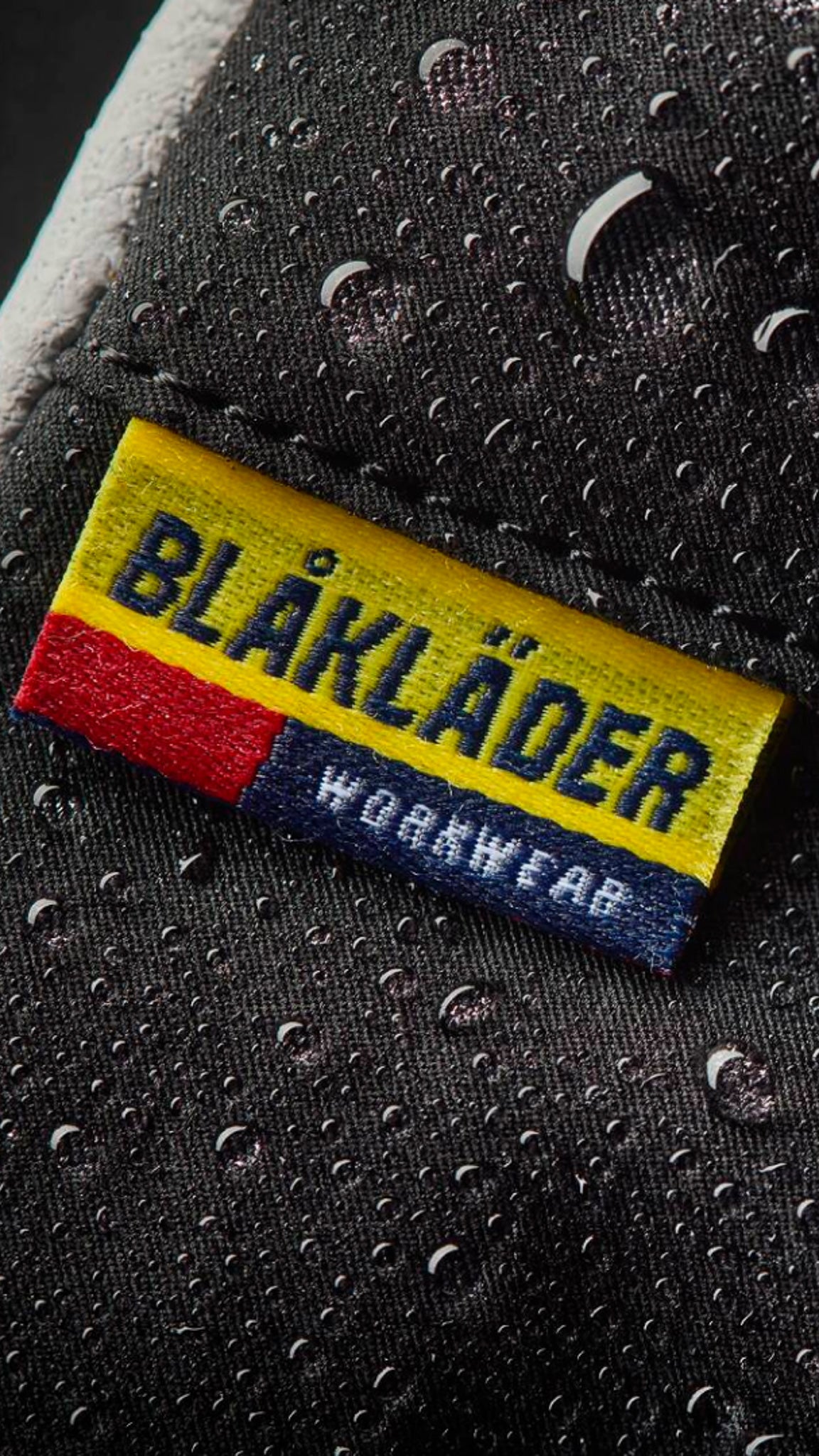 Blaklader workwear label on a textured surface with water droplets.