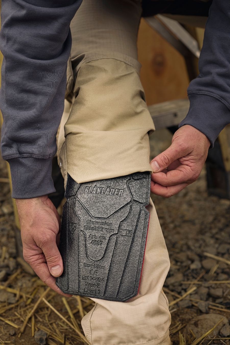 Tradesman inserting kneepad into work pants on a jobsite
